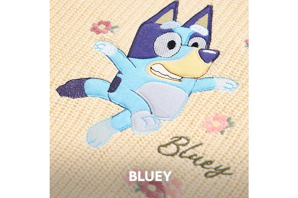 Close‑up of embroidered Bluey character on a beige fabric with small floral details.