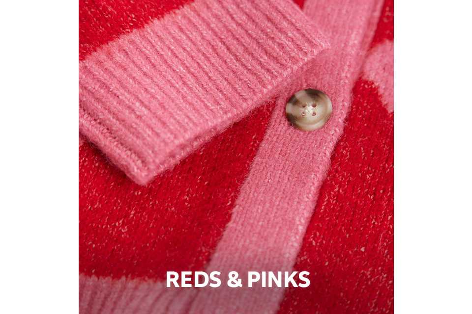 Close-up of soft red and pink knitwear with a button detail.
