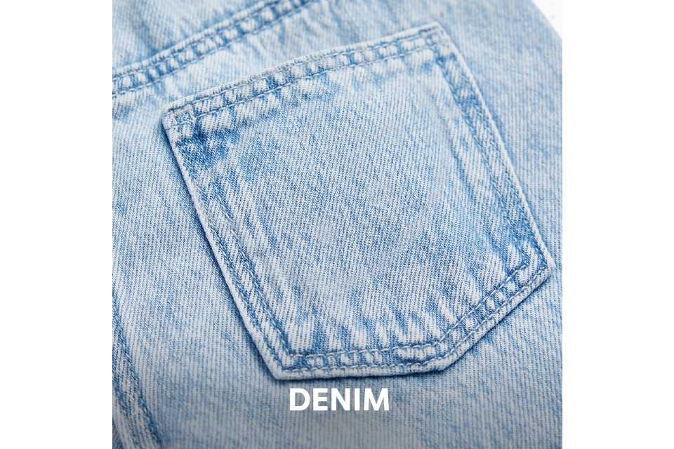 Close-up of light blue denim with visible stitching and a back pocket.