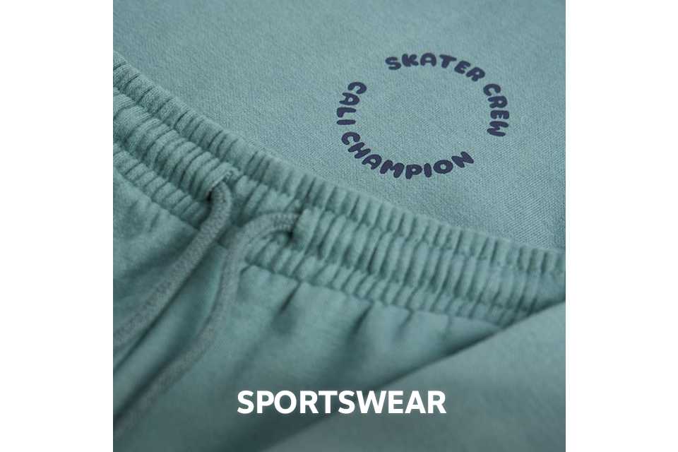 Close-up of green sportswear fabric with an elastic waistband and printed logo.
