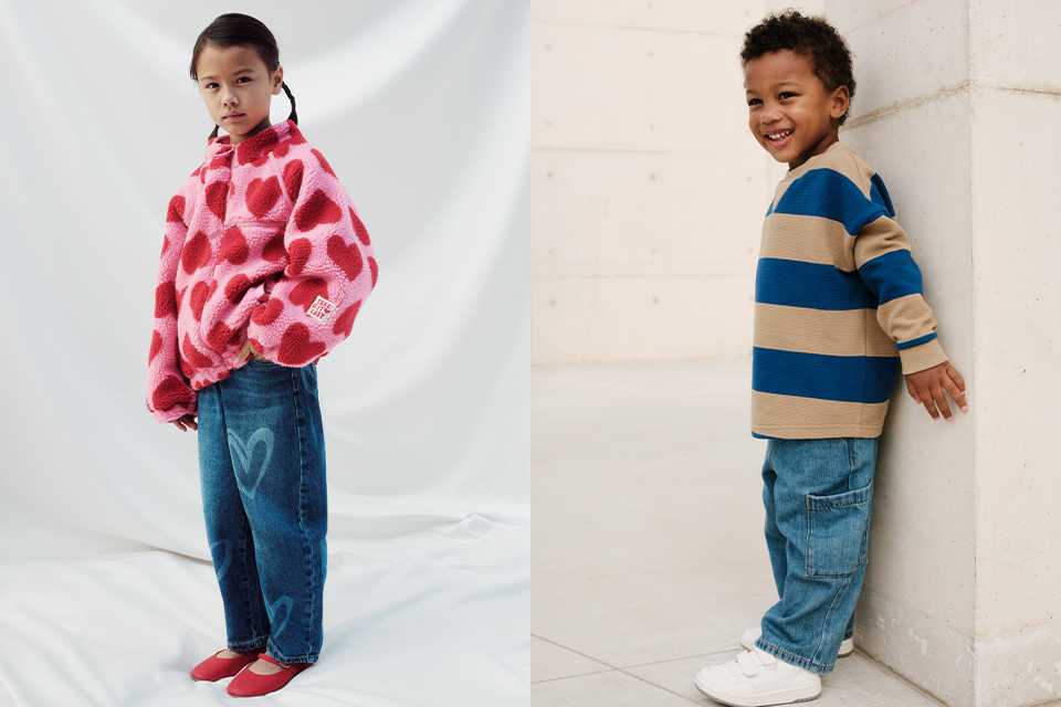Child in a pink heart-print fleece with blue jeans, next to another child wearing a blue-and-beige striped top and jeans.