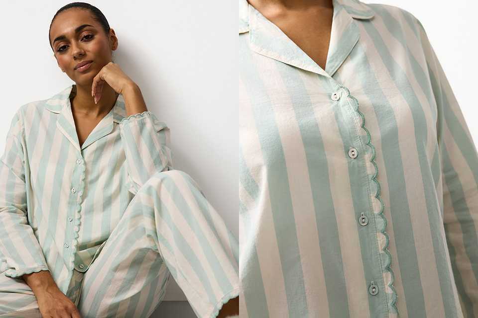 Person wearing a pink and red satin pajama set with a diamond pattern and decorative motifs, paired with beige slippers, standing against a plain white background.