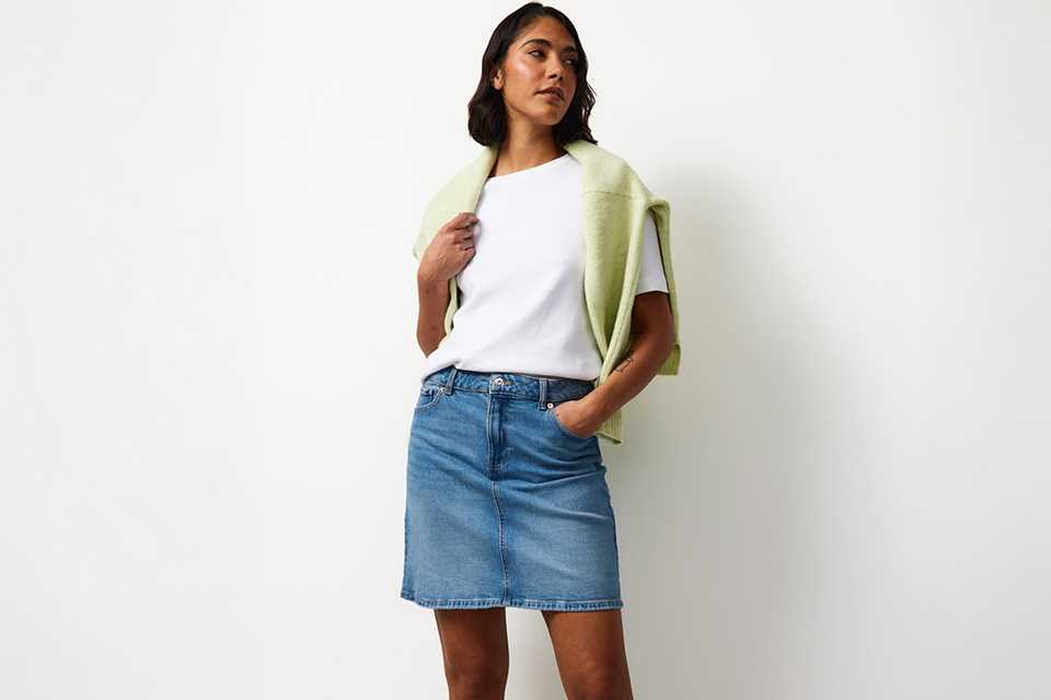 Capsule travel outfit with white T-shirt, wide-leg trousers and lightweight green layer for a city break.