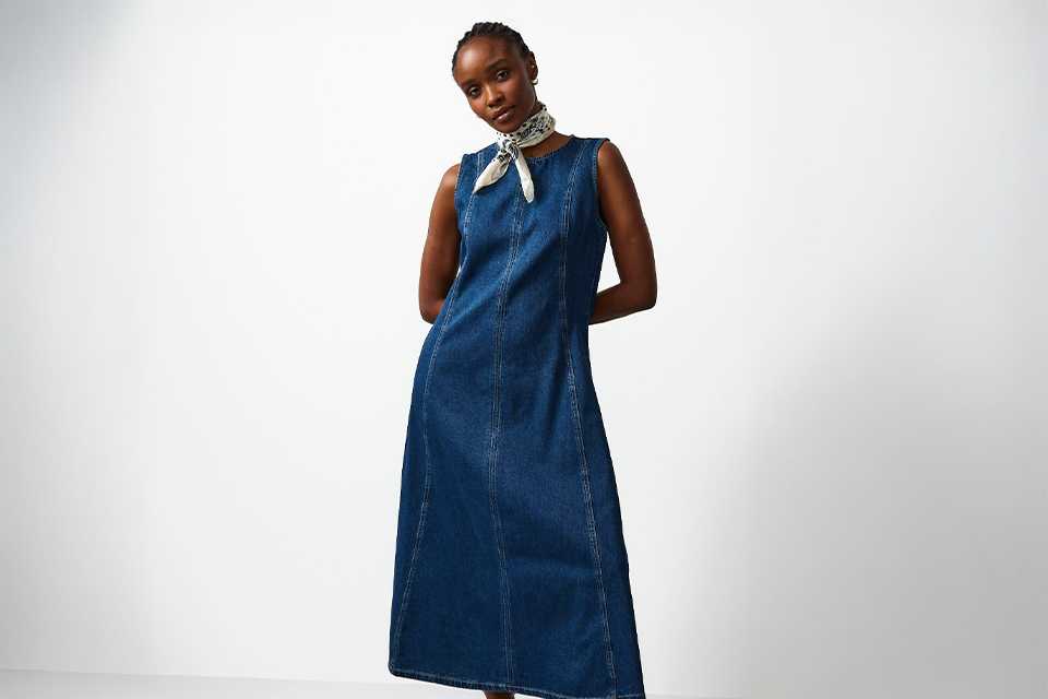 Casual wedding guest outfit featuring a sleeveless denim midi dress styled with statement accessories for a relaxed daytime wedding.