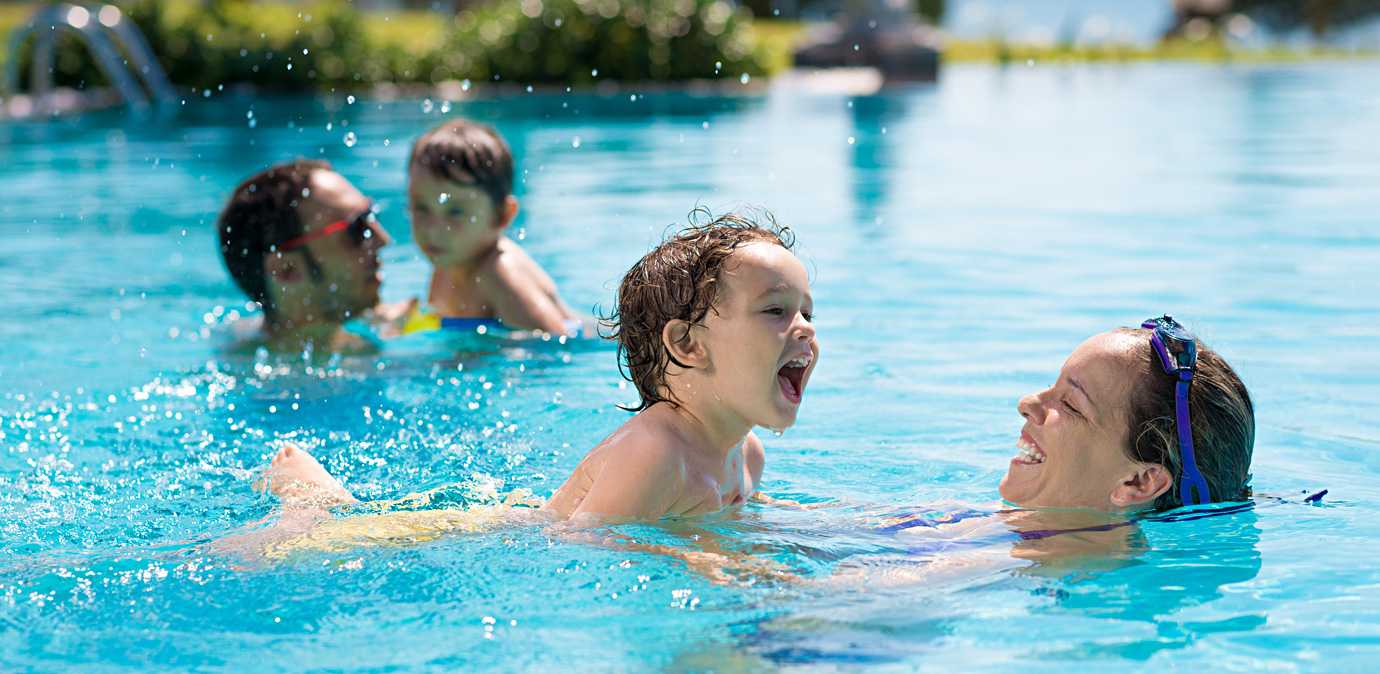 A little girl smiling while playing in a swimming pool.