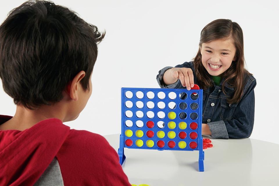 2 kids playing Connect 4 grid board game.