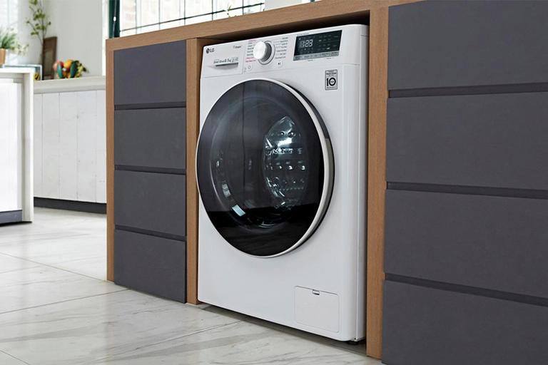 A white LG steam washer dryer integrated in a laundry room cabinet.