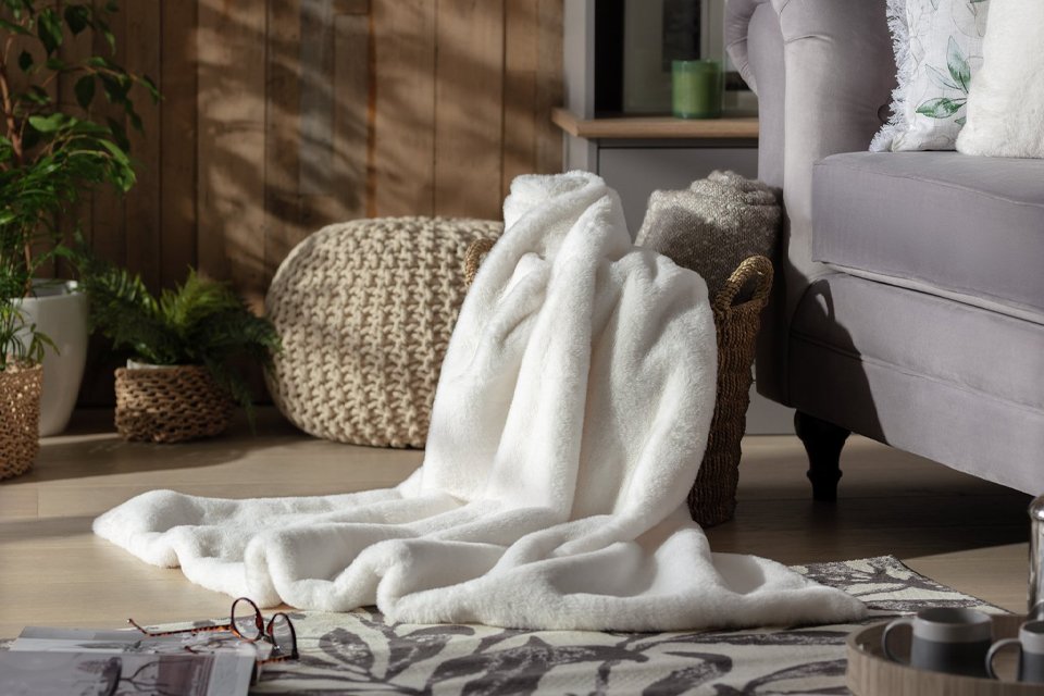Cream fur throw in living room basket next to sofa.