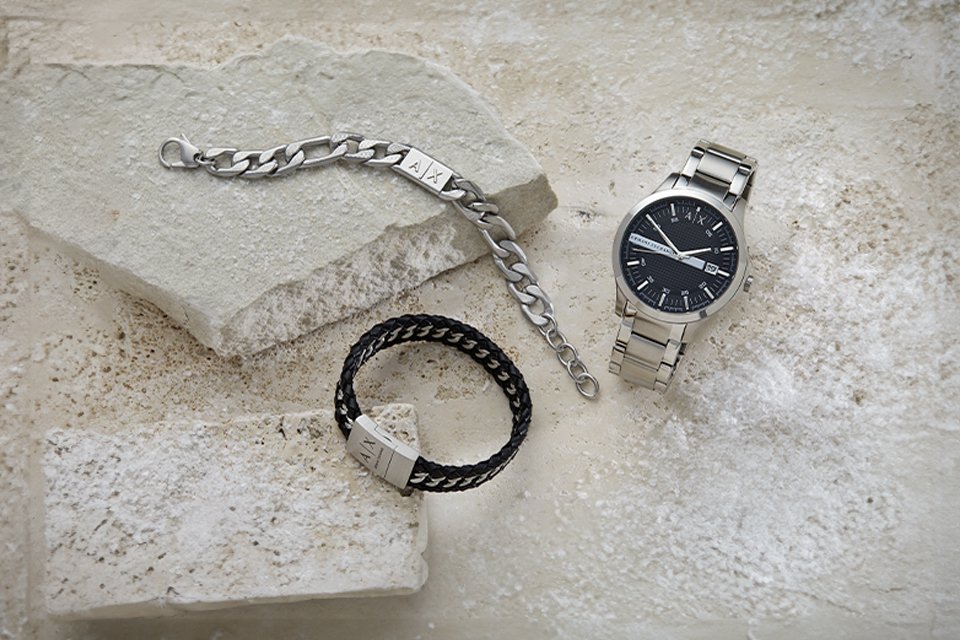 A bracelet and a watch for him against a white stone background.