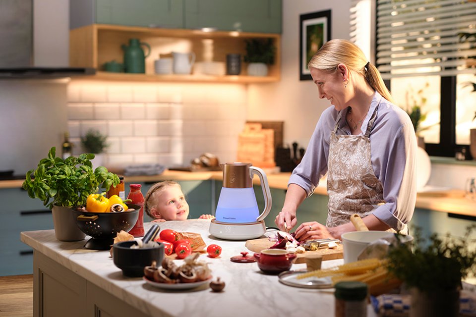 A Russell Hobbs Calm glass kettle is placed on kitchen countertop with mother and child looking on. 