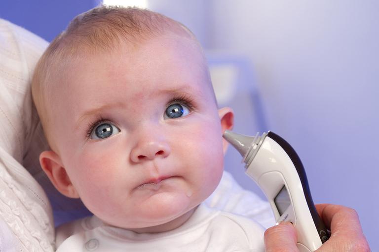 A parent using a ear thermometer on their baby.