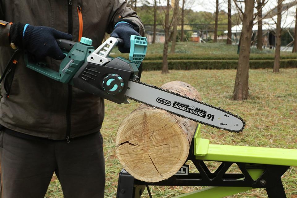 A man in a coat and gloves saws through a log with a chainsaw.
