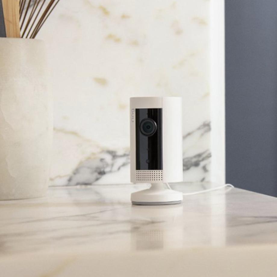 A white Ring indoor camera on a kitchen counter.