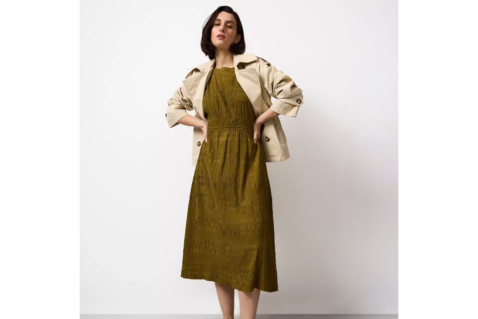 Light blue striped midi dress with short puff sleeves, V‑neckline and button‑front detail, styled with black ballet flats on a white background.