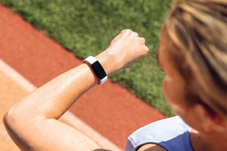 A woman checking her fitness tracker during her run.