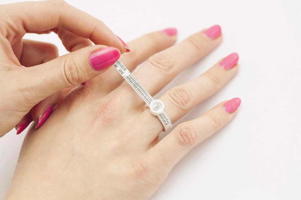 A woman measuring her ring size with a ring sizer tool.