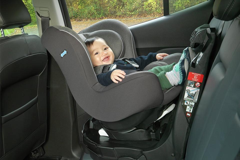 A smiling baby on a black car seat.