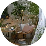 Cosy wicker garden chair and side table with warm string lights.