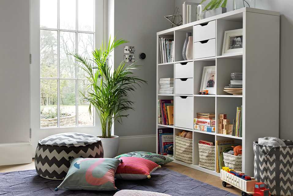A large, white cube bookcase in a grey living space with lots of floor cushions and storage baskets.