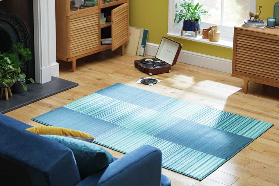 A blue patterned rug on a wooden living room floor.