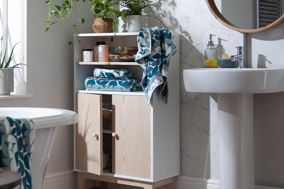 A white bathroom with a white and natural wood storage unit.