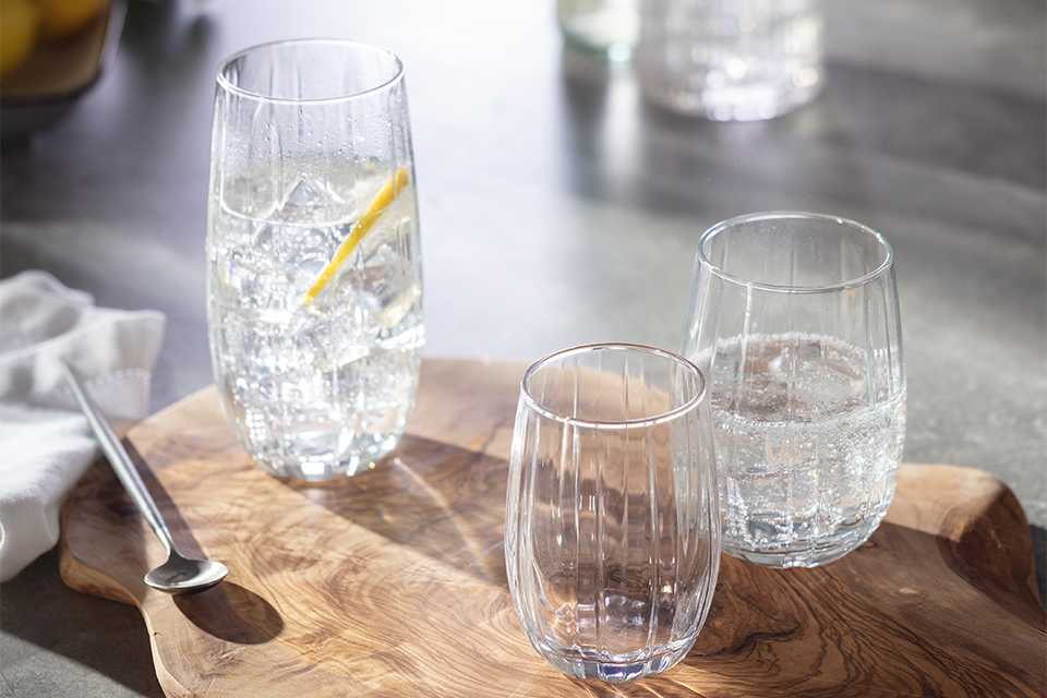 Three etched glasses on a tree slice chopping board.