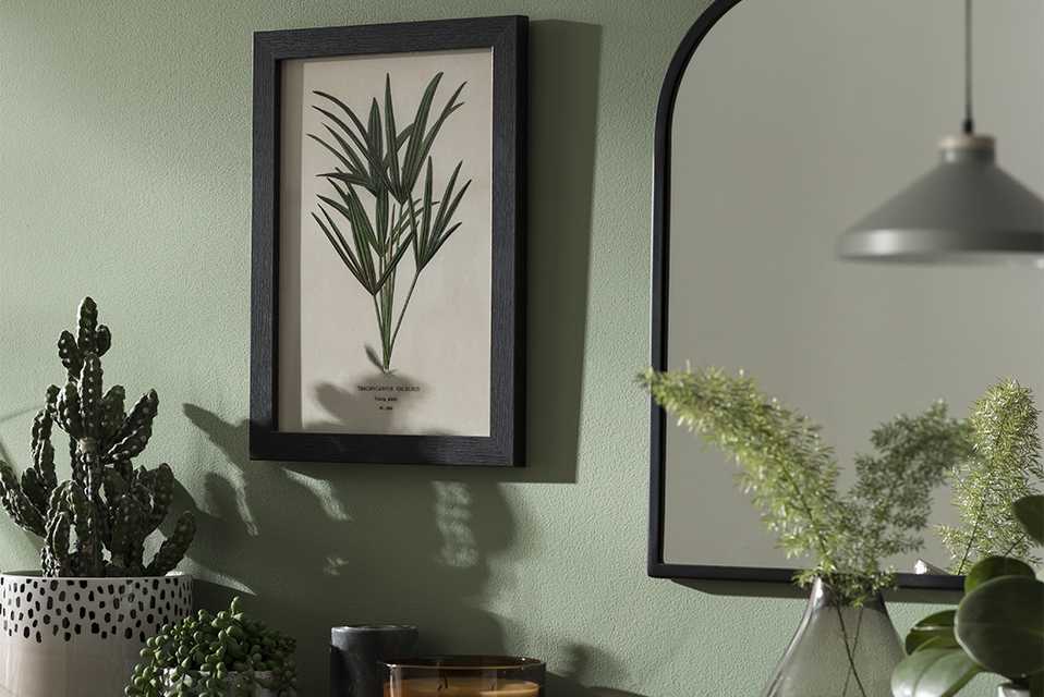 Black frame with wall art hanging on green wall.