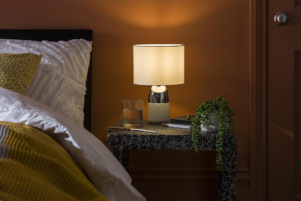 An image of a chrome and grey touch lamp on a bedside table.