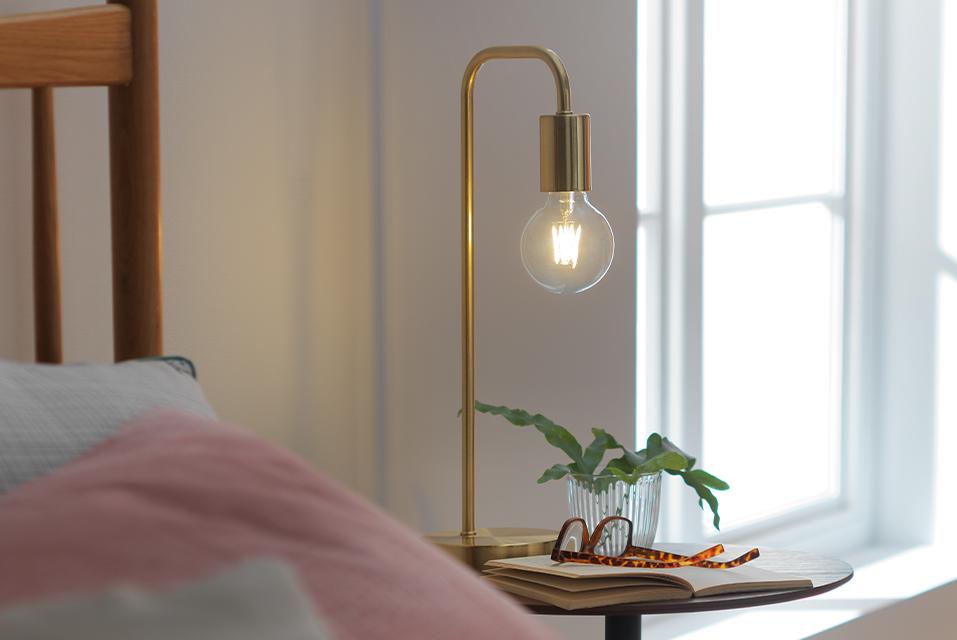 Image of a gold table lamp with an exposed bulb.