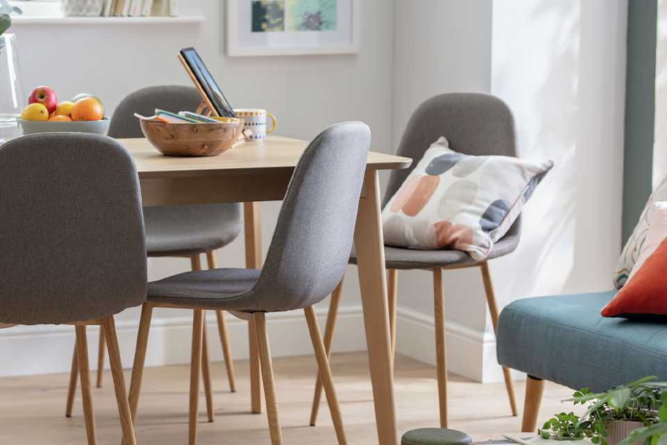 Grey upholstered dining chairs with rounded backs twinned with a Scandi-style dining table.