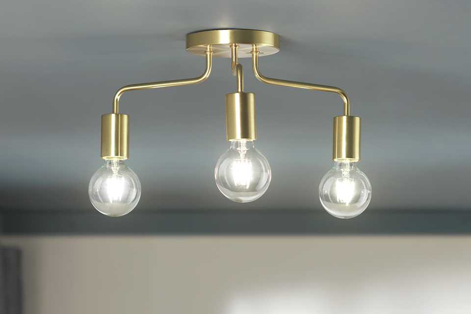 Image of a gold light bar with 3 exposed bulbs.