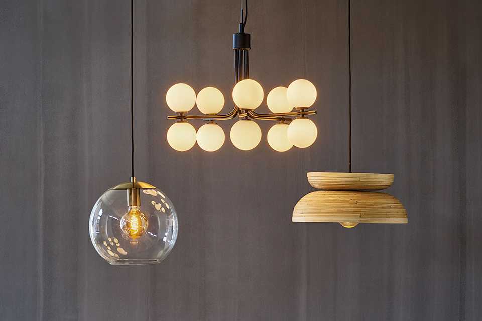 Image of three pendant lights in various styles hanging over a black dining table.