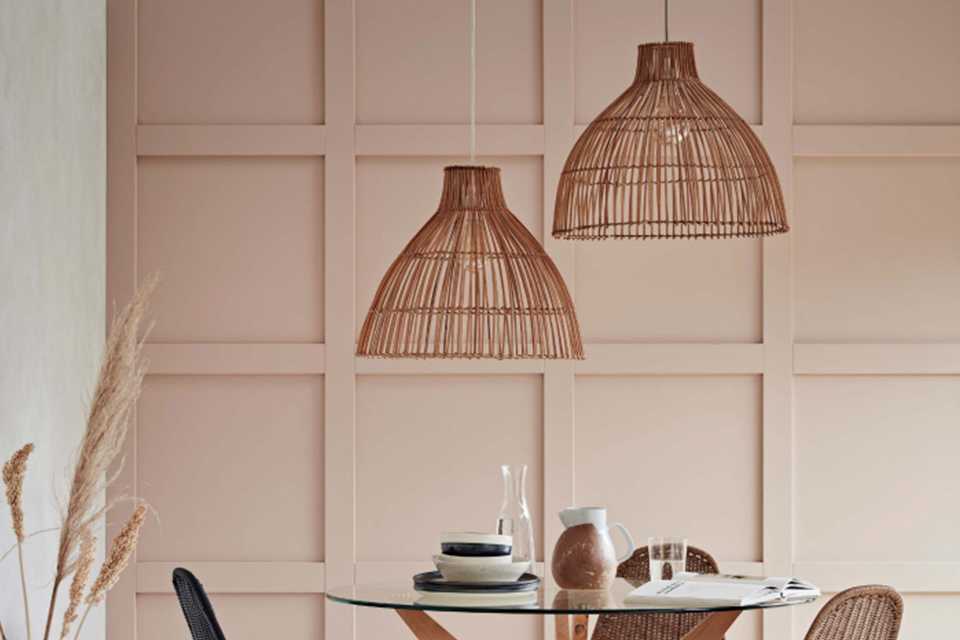 Image of a small dining table with two pendants hanging over it with rattan shades.