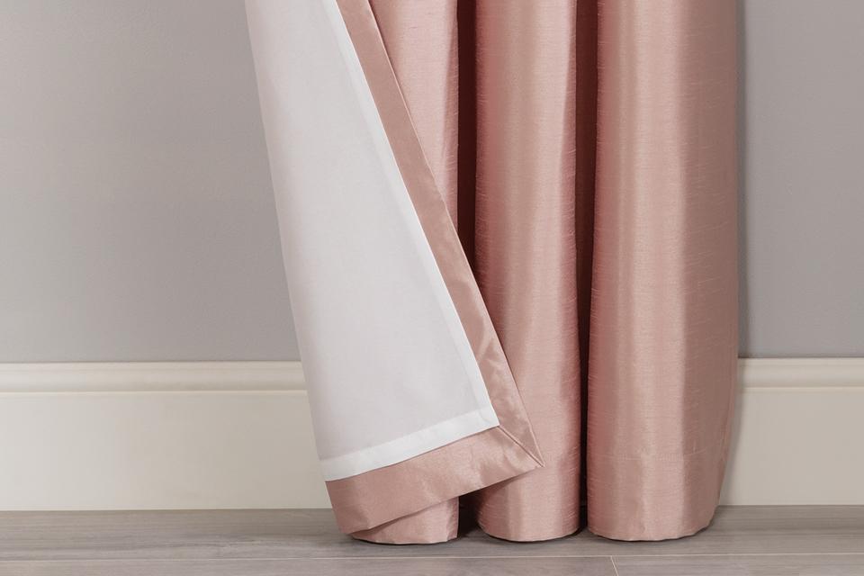A pink lined curtain against a grey and white wall.