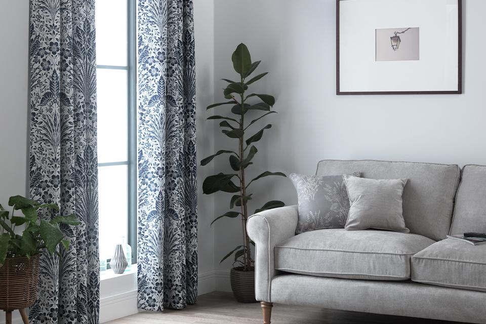 Living room with grey sofa and blue patterned curtains.
