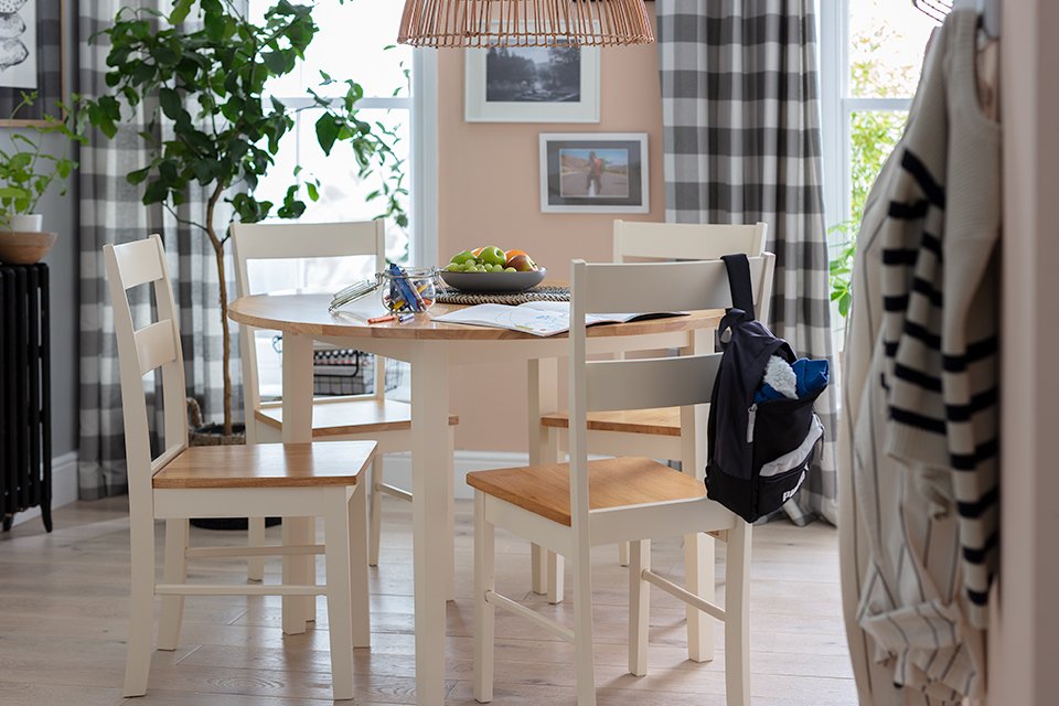 A white and natural wood round dining set in the middle of a dining space.