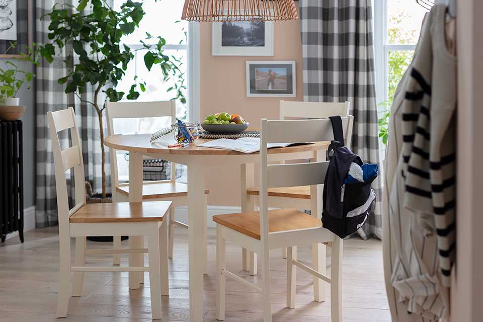 A white and natural wood round dining set in the middle of a dining space.