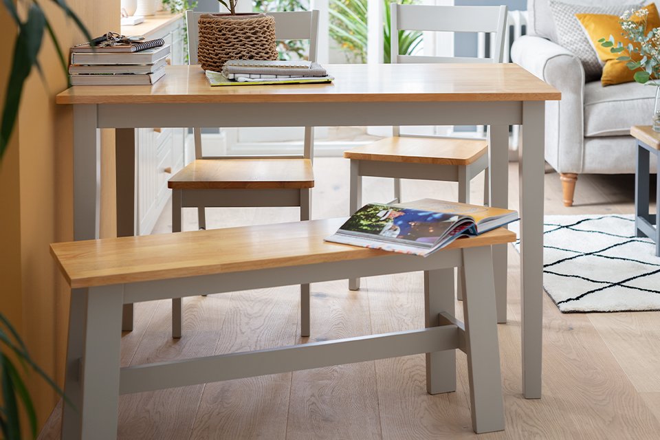 A grey and wooden dining table with matching benches in an open plan living space.