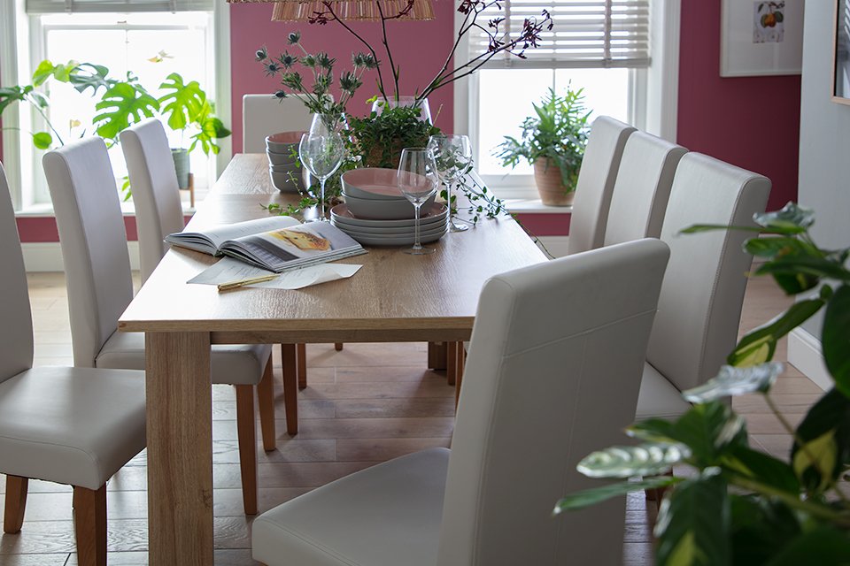 A long rectangular wooden dining table with matching upholstered chairs.