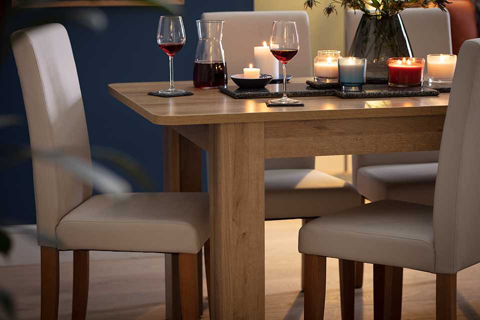 A natural wood rectangular dining set laid out for a meal with wine and candles.