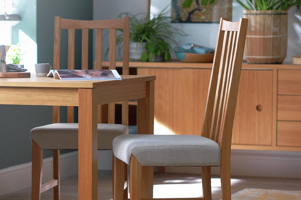 An oak dining set with a matching sideboard in the background with plant decor. 