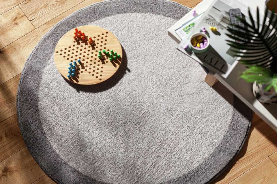 A round, two-tone grey rug with a game laid out on top of it.