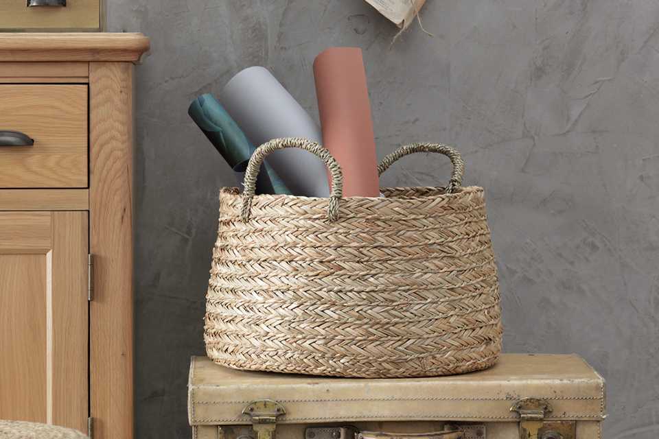 A rattan basket beside an oak cabinet.