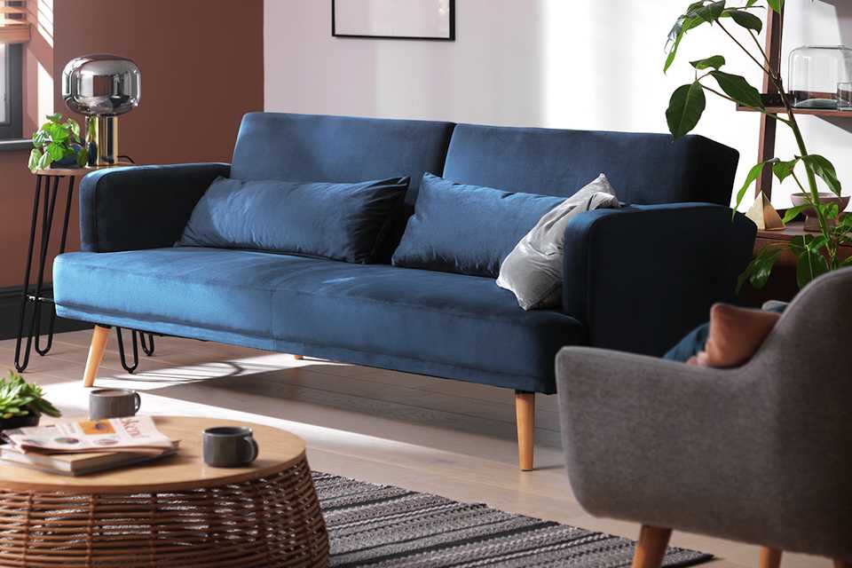 3 seater sofa bed in blue velvet material in living room.