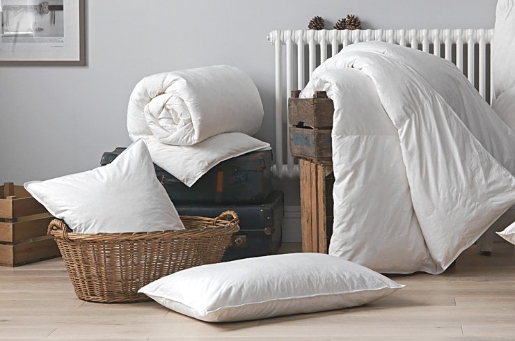 Duvet and pillows placed in a basket and on the floor.
