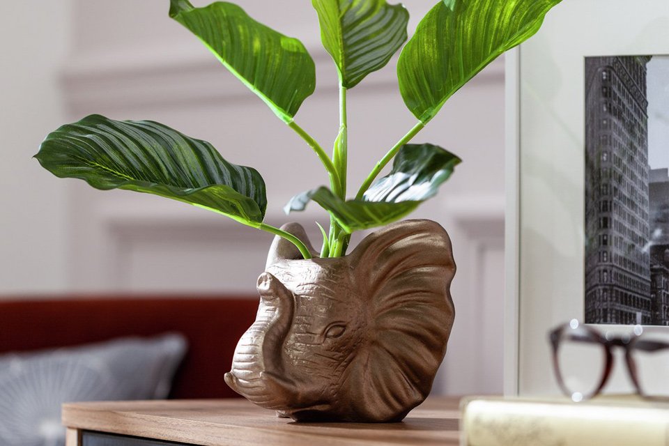 Artificial plant in elephant shaped pot.