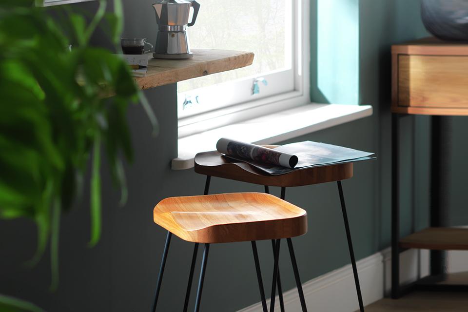 Breakfast bar stool next to a small wooden shelf, perfect for a coffee.