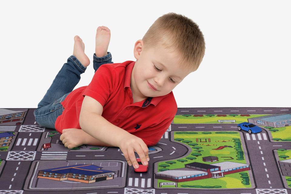 Un niño jugando con el tapete de juego de doble cara del Valle de Chad y el juego de autos.