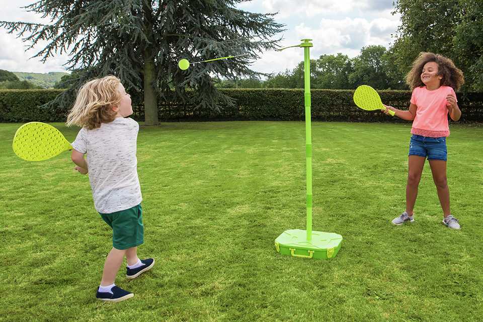 A boy and girl playing Early Fun Swingball All Surface in the garden.