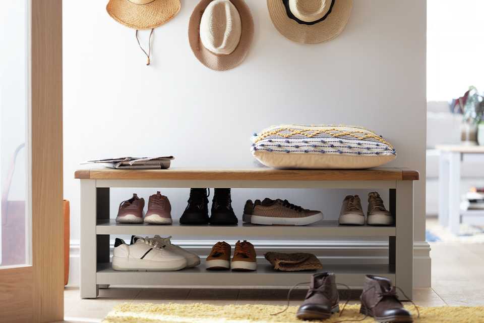 A white hallway with a grey and natural wood storage bench for shoes.
